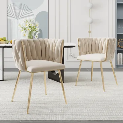 Two beige velvet dining chairs with gold legs are shown in a dining room setting.
