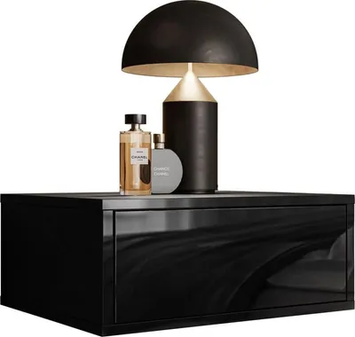 A modern black bedside table with two perfume bottles and a black and gold lamp on top.