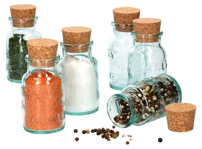 A collection of small glass jars with cork stoppers, some filled with spices and herbs, arranged on a white background.