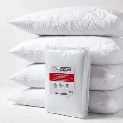 A stack of white quilted pillow protectors with one packaged in the foreground.