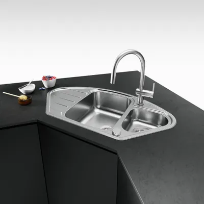 A stainless steel kitchen sink with a faucet, set on a black countertop.