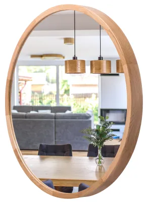 A round wooden mirror reflecting a dining room with a sofa, dining table, chairs, and pendant lights.