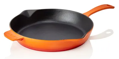 A studio shot of an orange cast iron frying pan on a white background.