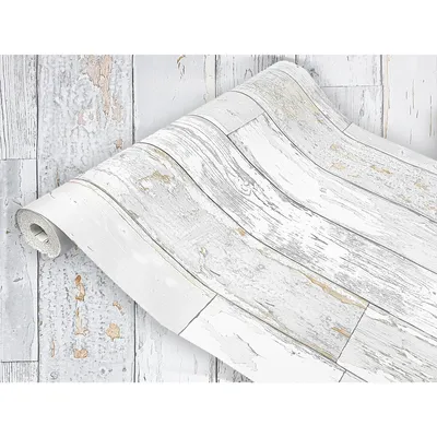 A roll of wood-effect wallpaper is partially unrolled, showing a distressed white wood plank design.