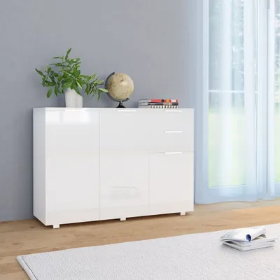 A white sideboard with a plant, globe, and books on top, placed in a room with a grey wall and a window with sheer curtains.