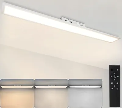 A long, rectangular LED ceiling light fixture is mounted on a white ceiling. Below the fixture, three smaller panels show the light at different color temperatures. A black remote control is visible on the right side.
