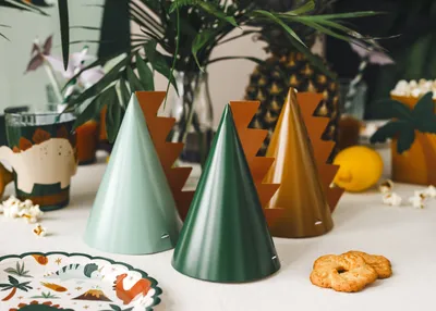 A table setting with dinosaur-themed party hats, plates, and decorations.