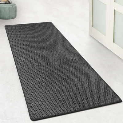 A dark gray rug with a textured pattern is laid out on a light-colored floor, next to a white cabinet with glass doors.
