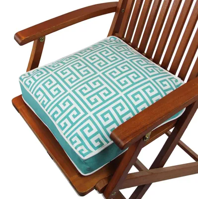 A close-up view of a teal and white patterned cushion on a wooden chair.