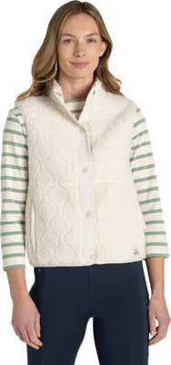 A woman wearing a cream-colored quilted vest over a striped long-sleeved shirt and navy leggings.