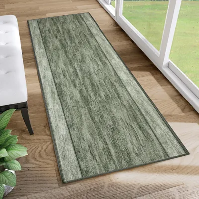 A runner rug with a wood plank design is placed on a wooden floor next to a white bench and a potted plant, with a large window in the background.