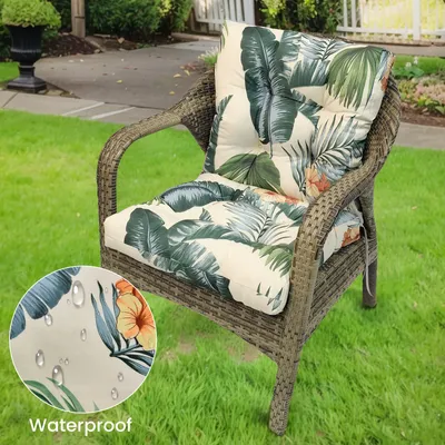 A chair cushion with a tropical leaf pattern is placed on a wicker chair outdoors.