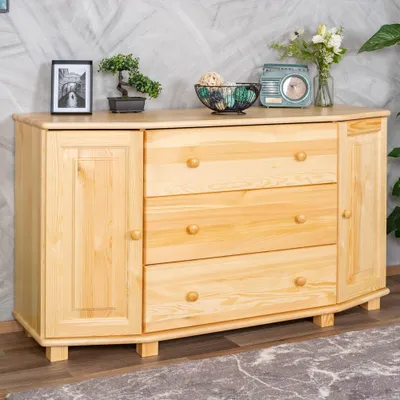 A wooden sideboard with drawers and doors, decorated with a bonsai tree, a framed picture, a decorative bowl, and a vintage radio.