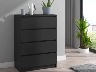 A black dresser with four drawers is shown in a room setting.