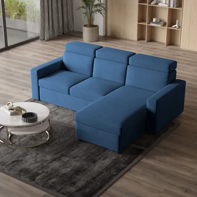A blue sectional sofa is shown in a modern living room setting, with a coffee table and rug in the foreground and shelves in the background.