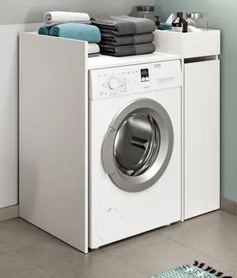 A white washing machine is shown integrated into a white cabinet unit, with folded towels on top.
