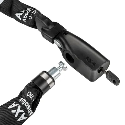 A close-up of a black bicycle chain lock with a silver locking pin and a key inserted into the lock mechanism.