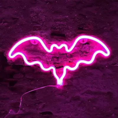 A pink neon bat-shaped light is mounted on a dark, textured brick wall.