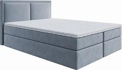 A studio shot of a gray upholstered box spring bed with a white mattress and topper.