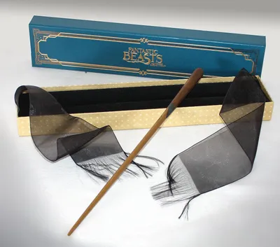 A Newt Scamander wand from Fantastic Beasts is displayed with its packaging and decorative ribbon.