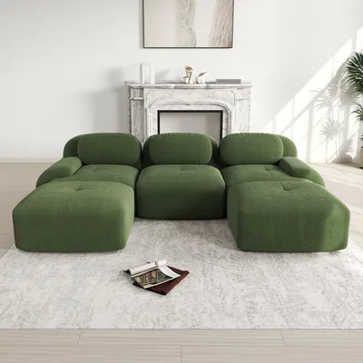 A green modular U-shaped sofa is placed on a light-colored rug in front of a fireplace.