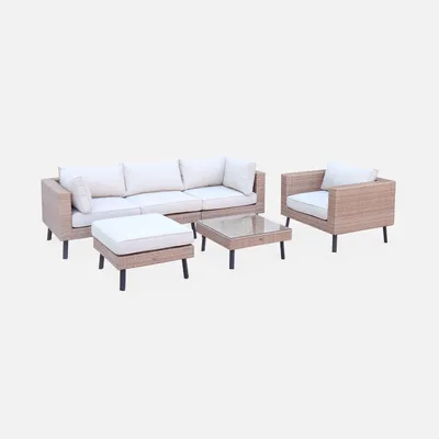 A beige polyrattan garden furniture set with white cushions, including a sofa, armchair, coffee table, and ottoman, displayed on a white background.