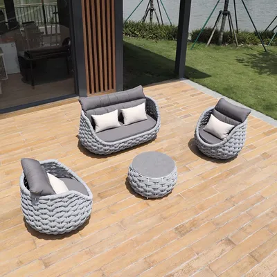 An outdoor furniture set on a wooden deck next to a lawn and a body of water.