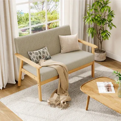 A cozy living room scene featuring a beige loveseat, a wooden coffee table with a magazine, and a potted plant.