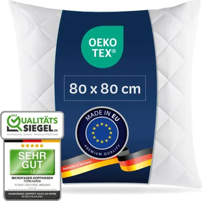 A white quilted pillow with a dark blue label featuring product information and certifications.