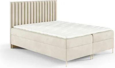 A beige boxspring bed with a fluted headboard and gold legs, shown against a white background.