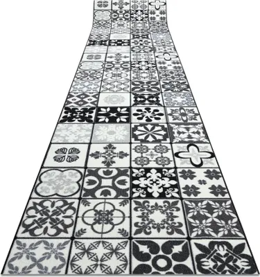 A long hallway runner rug with a patchwork tile pattern in gray and black.