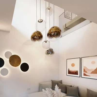 A modern living room with a sectional sofa, abstract wall art, and a cluster of pendant lights.