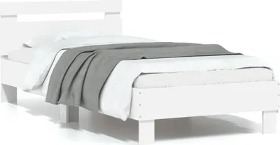 A white wooden bed frame with a grey blanket and white bedding.