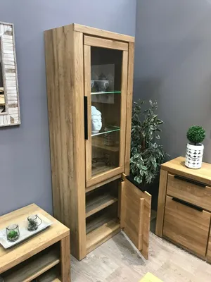 A tall wooden display cabinet with glass doors and open shelves, placed in a room setting.