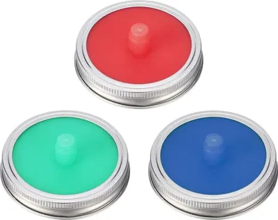 Three fermentation lids in red, green, and blue, each with a silver metal rim, are arranged in a triangular formation against a white background.