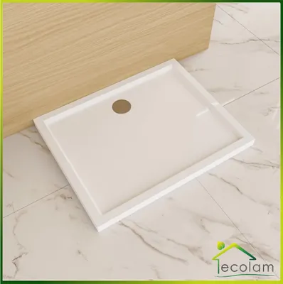 A white rectangular shower tray with a circular drain is placed on a marble-tiled floor next to a wooden panel.
