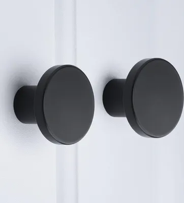 Two black, round knobs are mounted on a white surface.