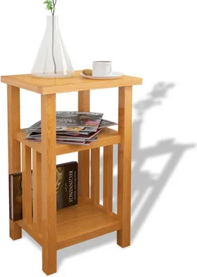A wooden side table with two shelves, a vase with a plant, a cup of coffee, and some books and magazines.