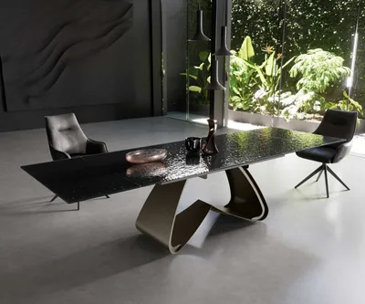 A modern dining room with a large table and chairs, featuring a view of lush greenery through a large window.