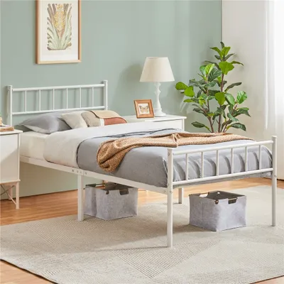 A white metal bed frame with bedding and storage bins underneath, set in a bedroom.