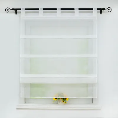 A white sheer Roman blind hangs on a window, with a small pot of sunflowers on the windowsill below.