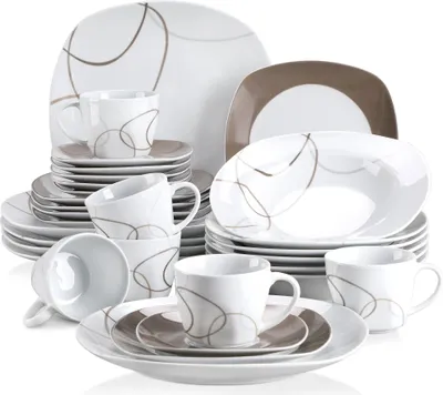 A collection of white ceramic dinnerware with a brown abstract design, arranged in a studio setting.