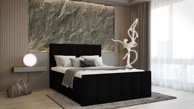 A modern bedroom with a black upholstered bed, a stone-textured wall, and a sculptural lamp.