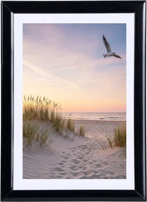 A framed photograph of a beach scene at sunset with a seagull flying.