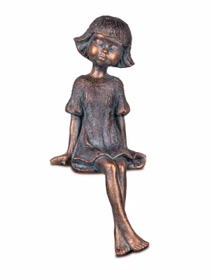 A bronze-colored figurine of a young girl sitting with her eyes closed.