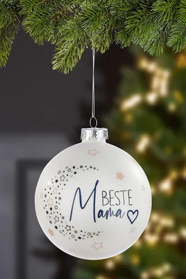 A white Christmas ornament with stars and the text 'Beste Mama' hangs from a pine branch.