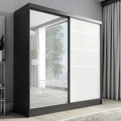 A modern sliding door wardrobe with a mirrored front panel and white panels, set in a room with curtains and a rug.