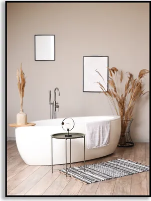A modern bathroom with a freestanding bathtub, decorative plants, and artwork on the wall.