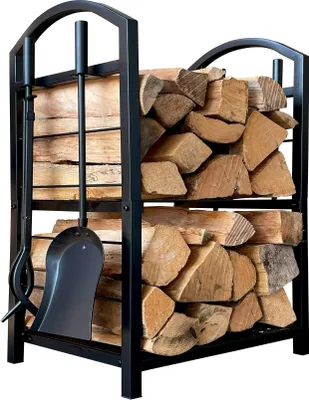 A black metal firewood rack filled with logs, with a set of fireplace tools hanging on the side.
