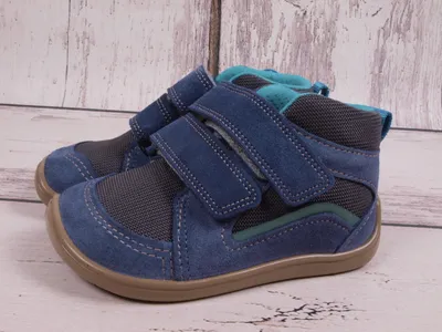 A pair of blue children's shoes with velcro straps on a light wooden background.